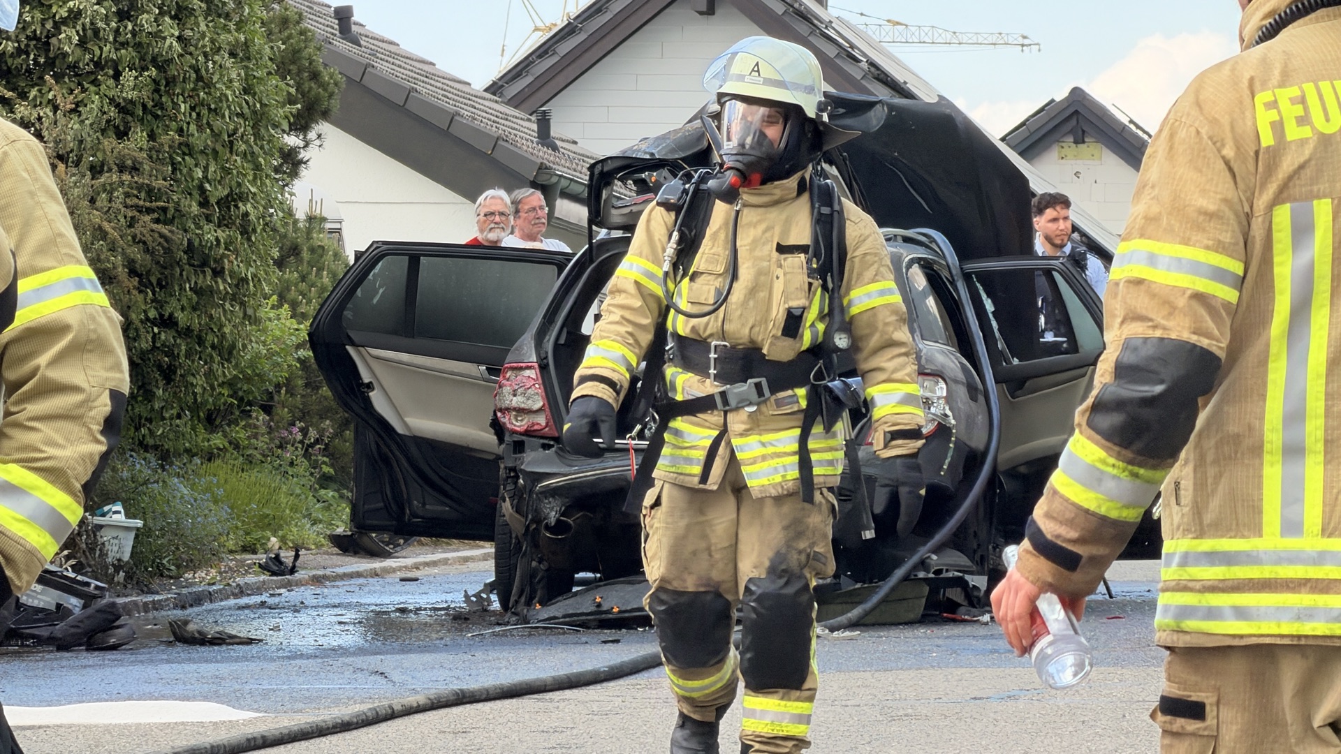 Feuerwehrmann mit Atemschutzausrüstung vor einem verunfallten Fahrzeug